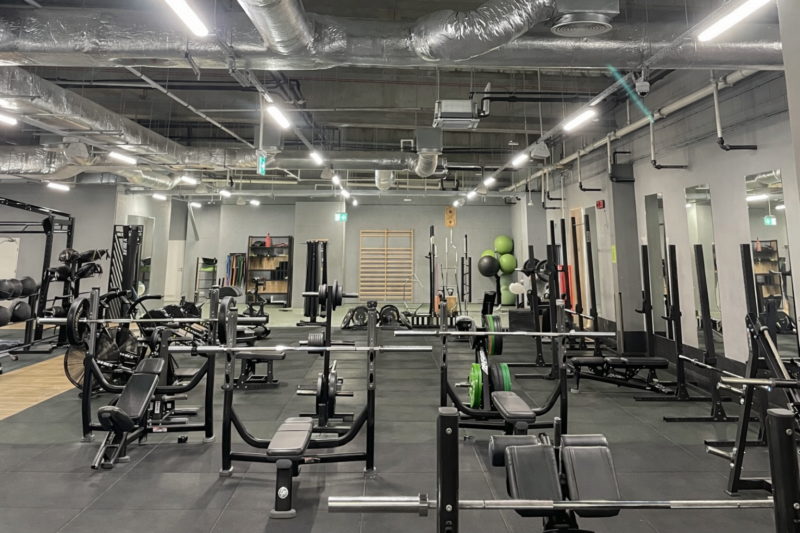 Простора зона вільних ваг зі штангами та лавками у тренажерному залі Well Fitness у Вроцлаві (Карловіце).
