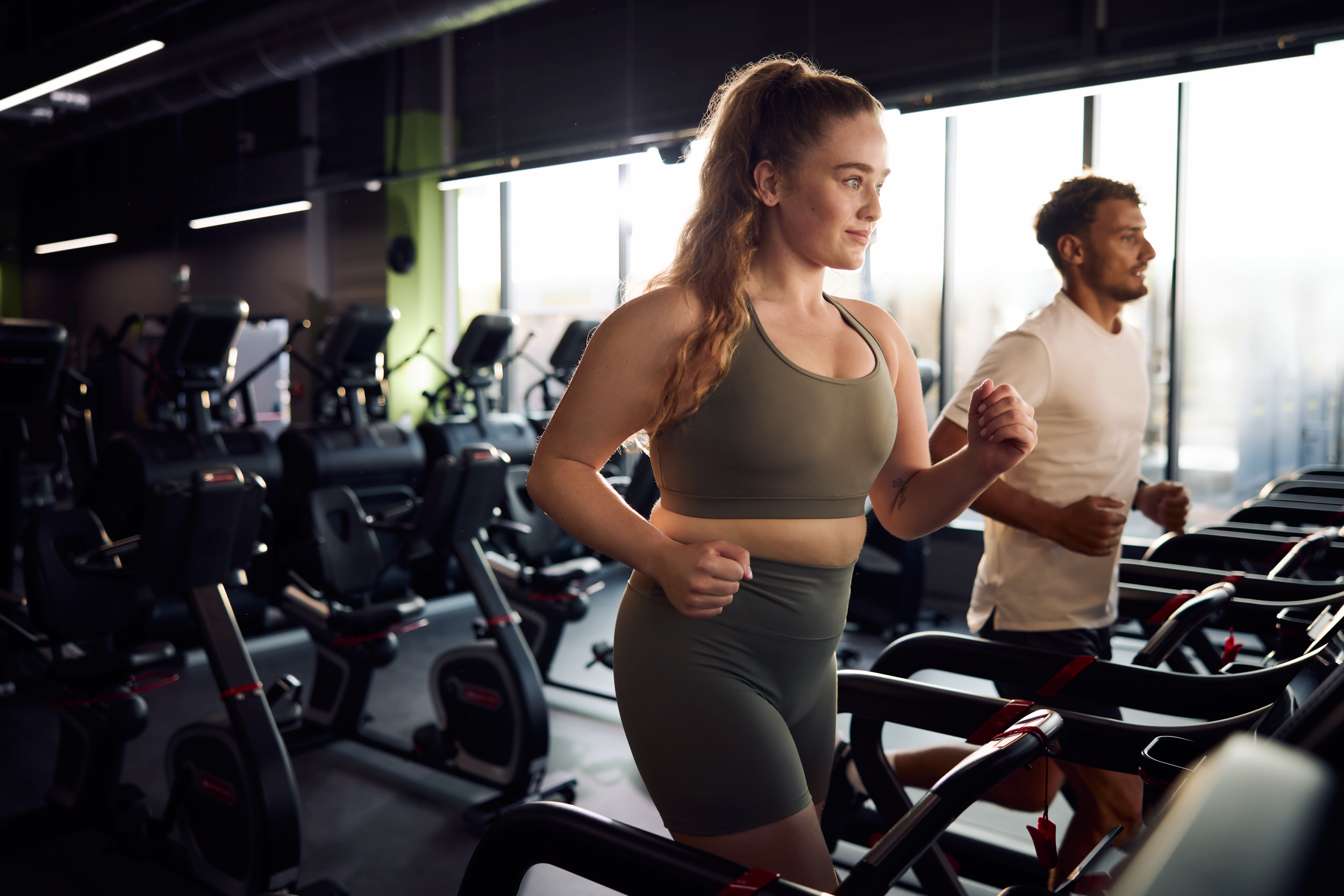 Жінка та чоловік тренуються на біговій доріжці у Well Fitness