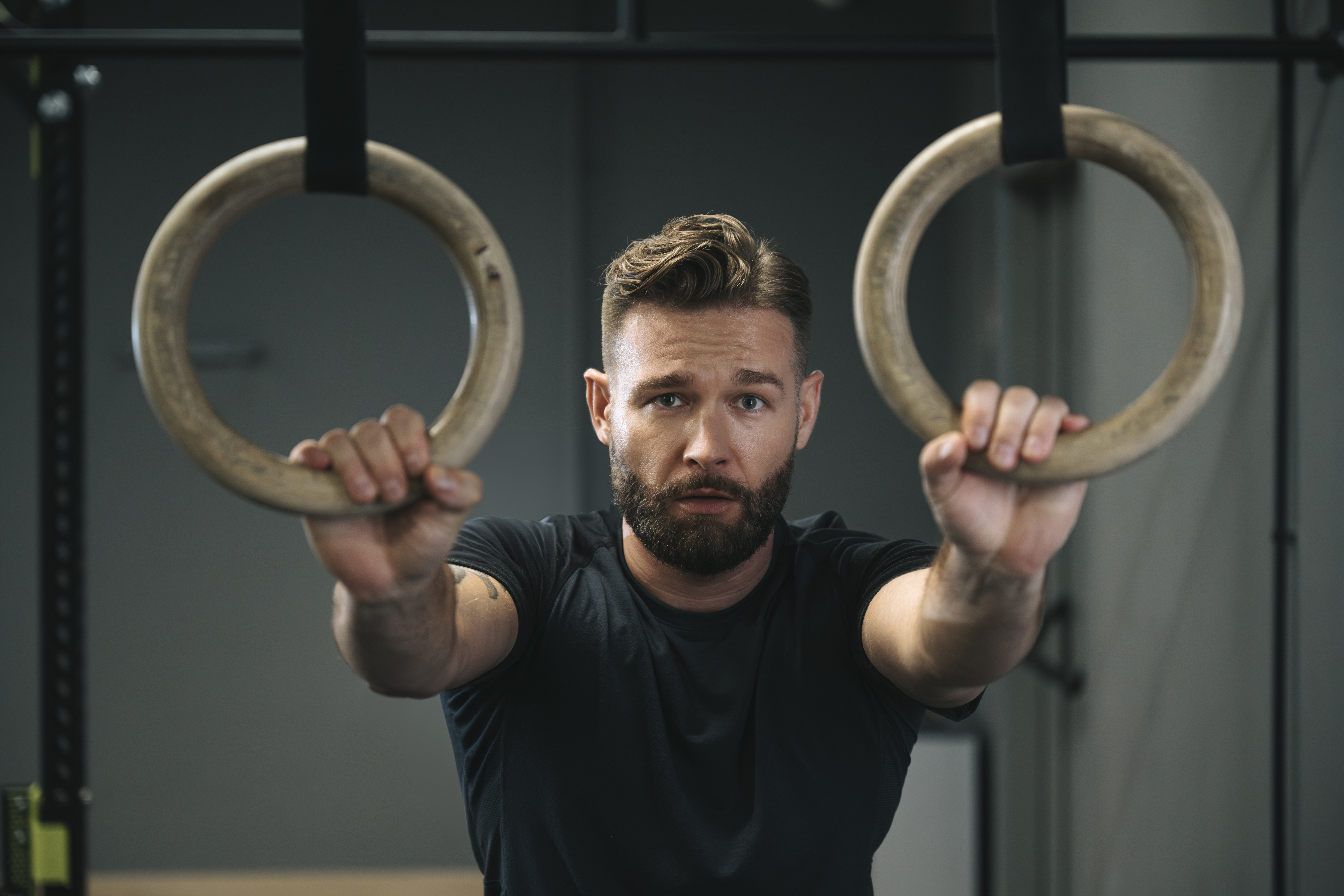 Mężczyzna trzymający pierścienie gimnastyczne do kalisteniki w well fitness