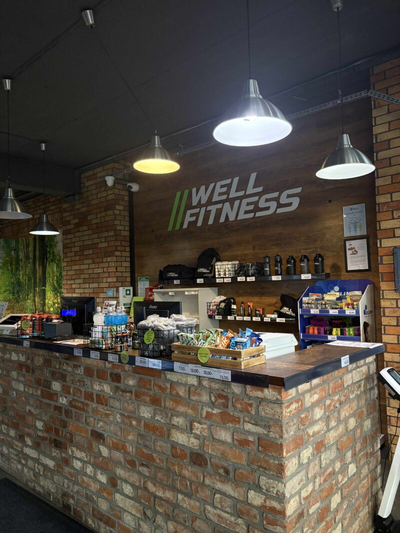 Рецепція фітнес-клубу Well Fitness з персоналом і стійкою реєстрації.
