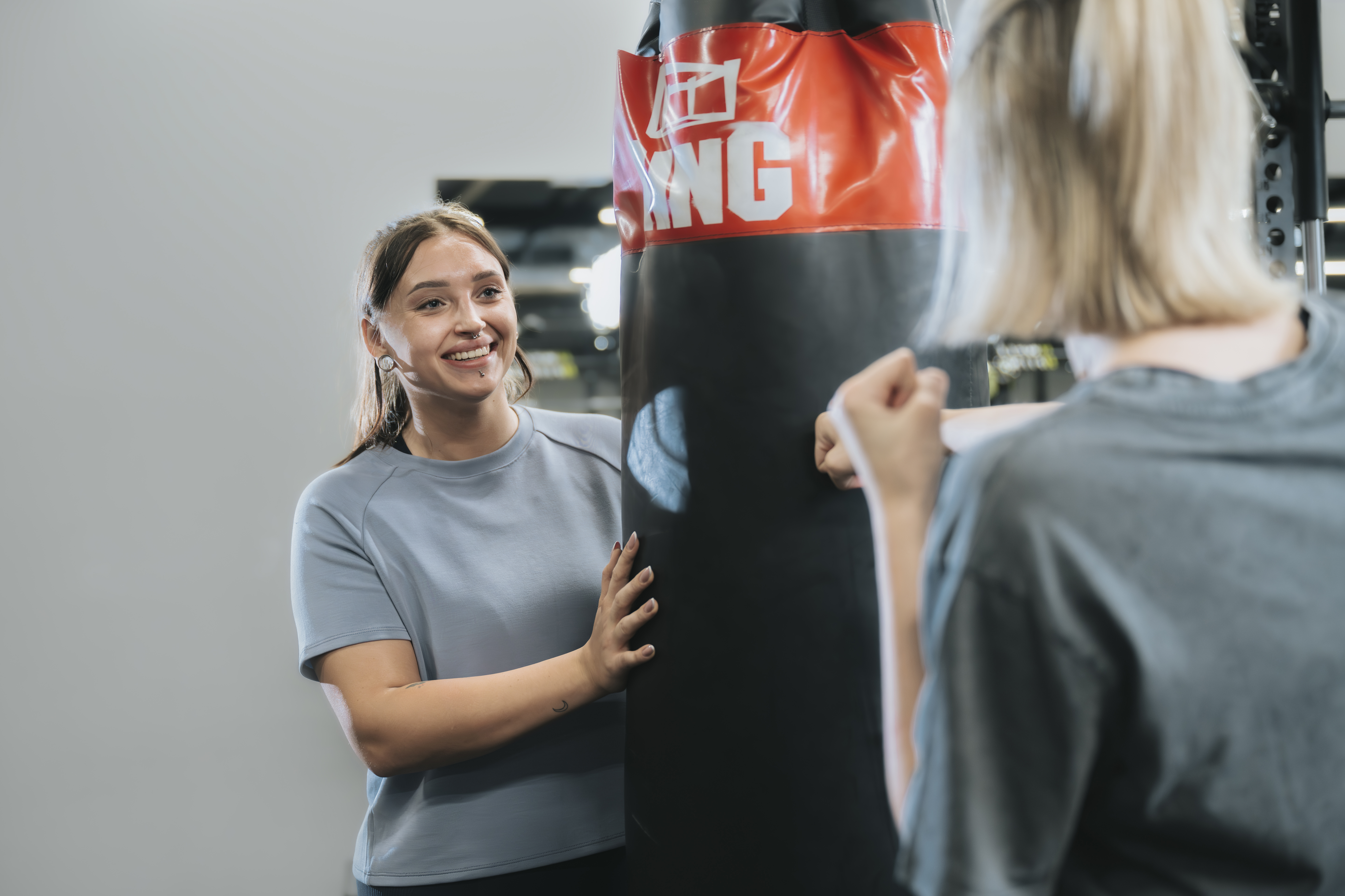 Dwie kobiety przy worku treningowym na siłowni