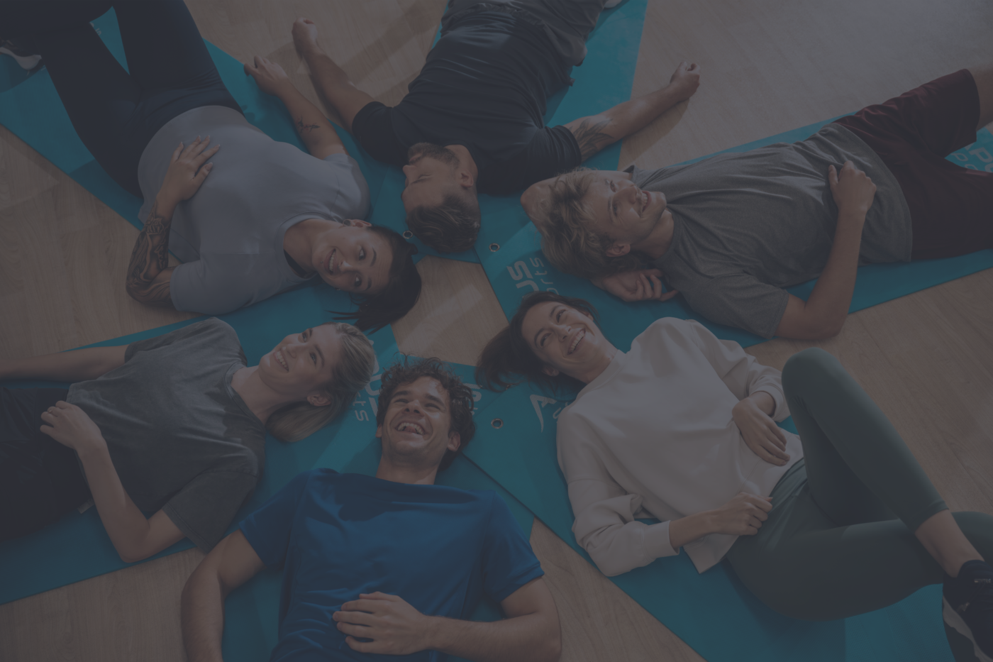 Grupa ludzi leżących na matach po zajęciach w well fitness