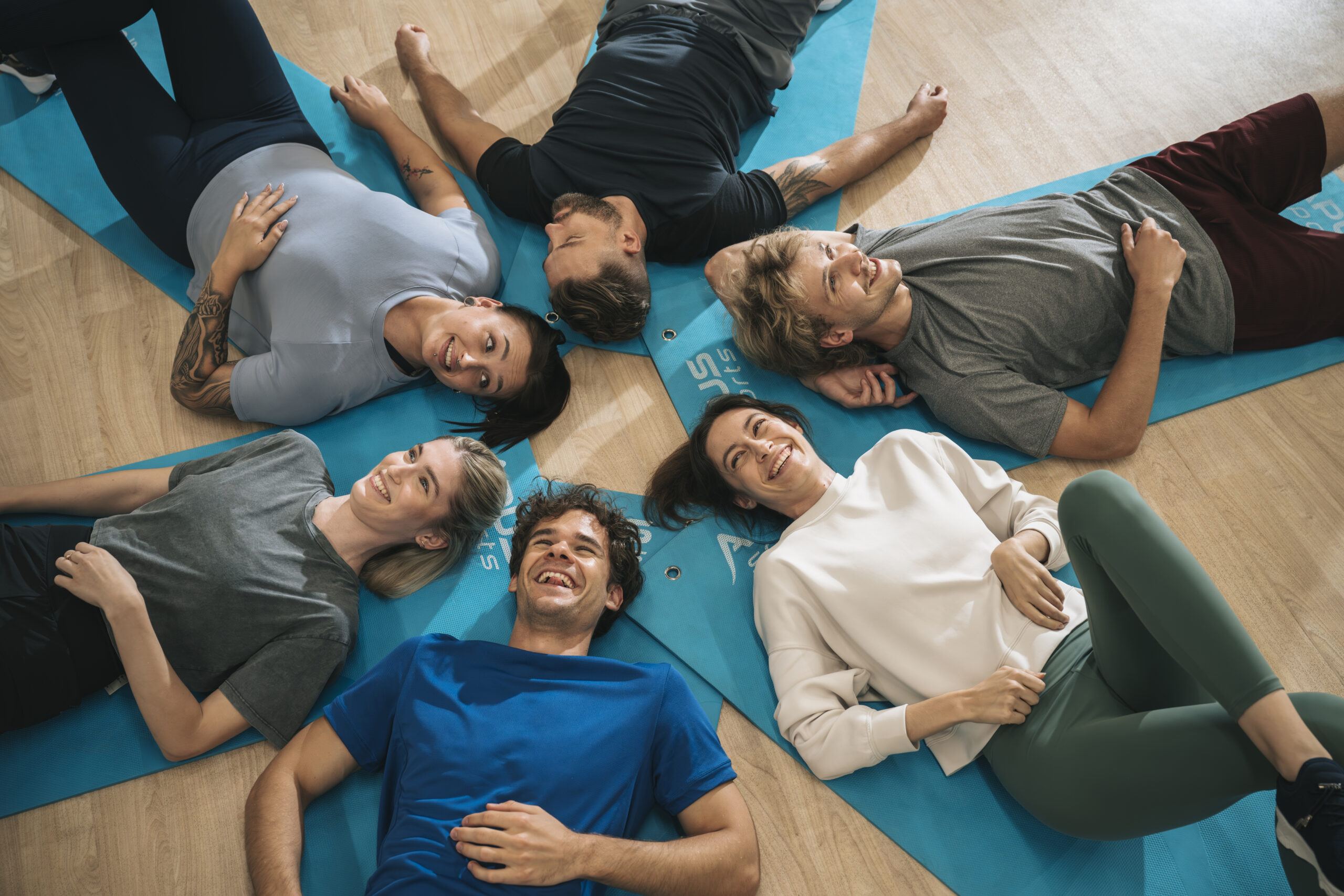 grupa zadowlonych ludzi leżących na matach do ćwiczeń