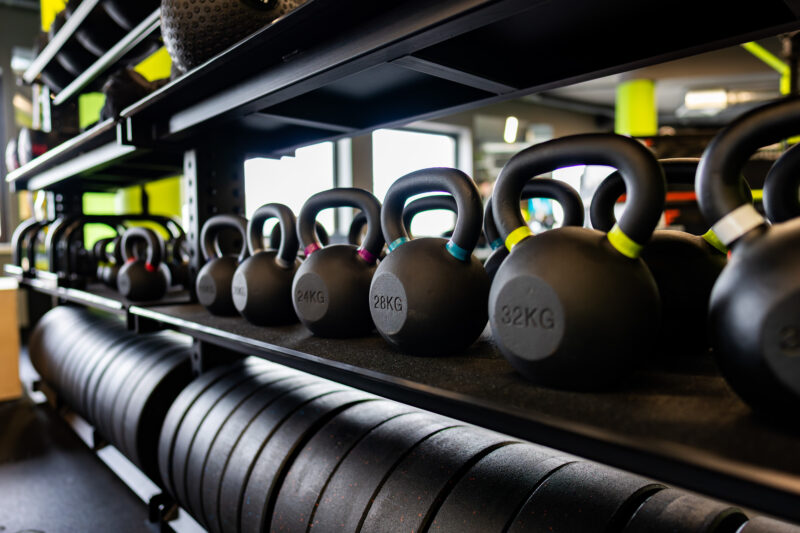 Чорні гирі різної ваги на стелажі в тренажерному залі Well Fitness