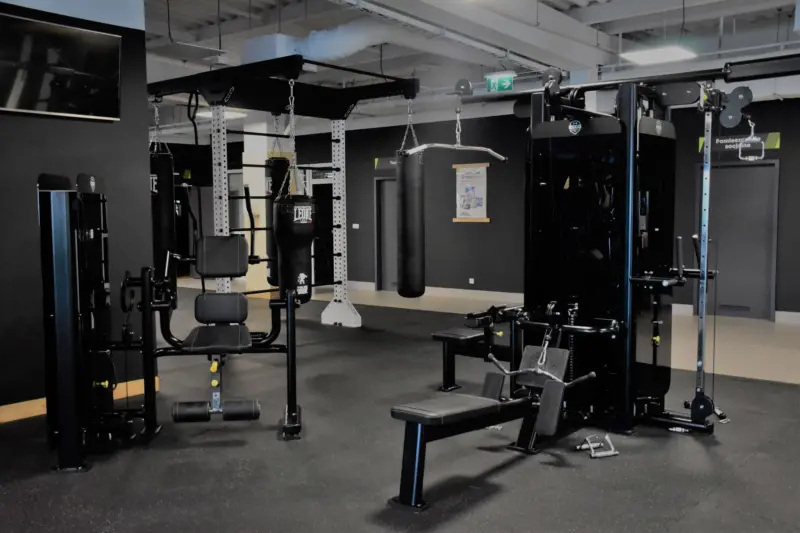 Wnętrze siłowni z wyciągiem oraz maszynami do treningu izolowanego.