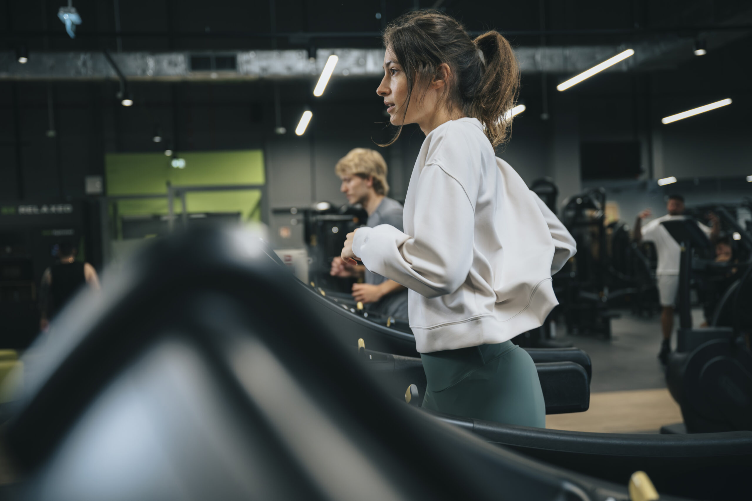 Kobieta biegnąca po bieżni w Well Fitness