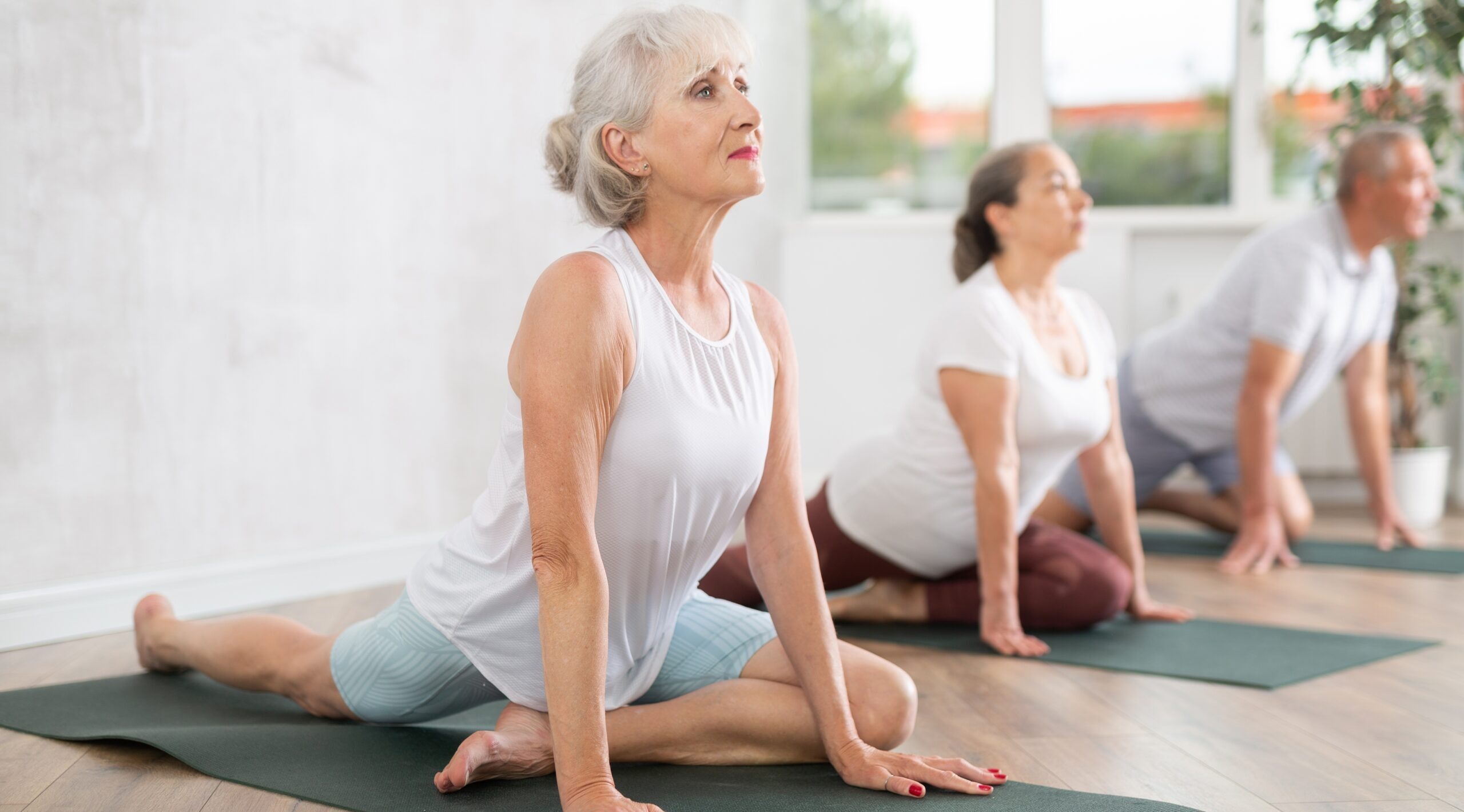 Trójka seniorów ćwicząca na matach podczas zajęć aktywny senior