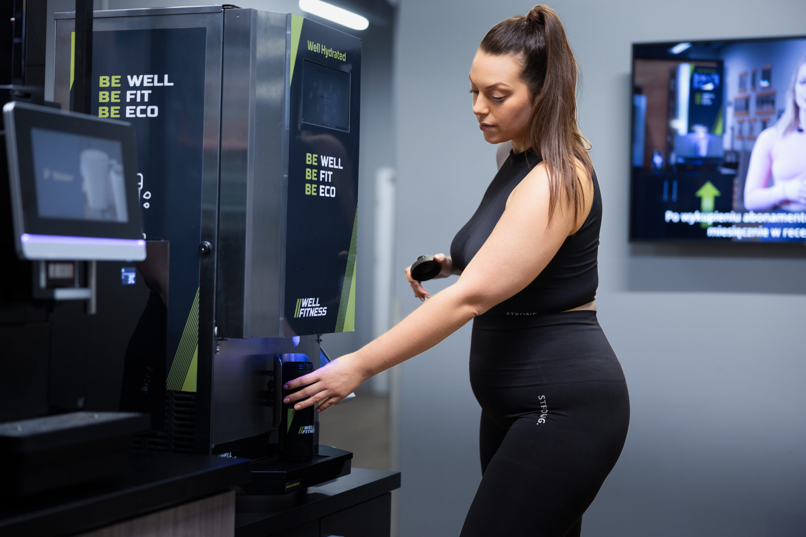 kobieta korzystająca z maszyny well hydrated - napełnia butelkę