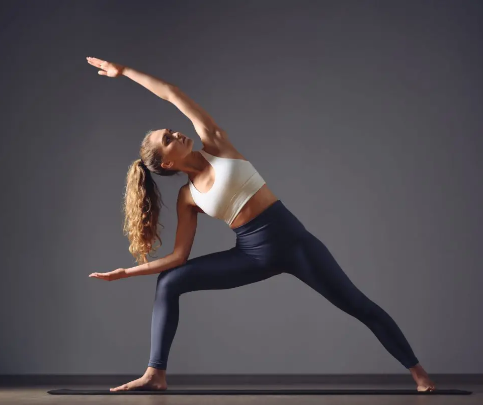 Kobieta w pozycji jogi w Well Fitness, wykonująca rozciągające ćwiczenie boczne na macie