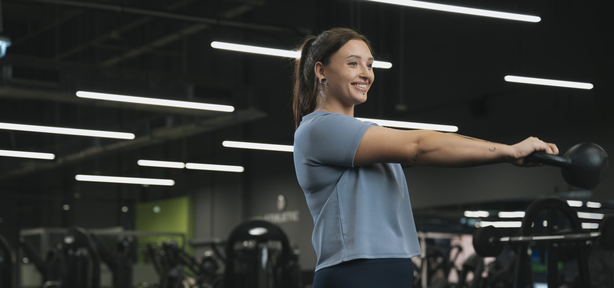 Kobieta ćwicząca w Well Fitness, wykonująca swing z kettlebell na siłowni
