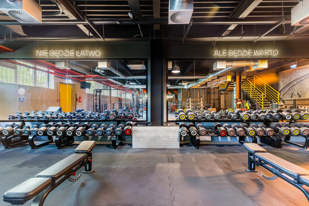 Strefa hantli w Well Fitness Reymonta w Krakowie z motywacyjnym napisem na lustrze "Nie będzie łatwo, ale będzie warto".