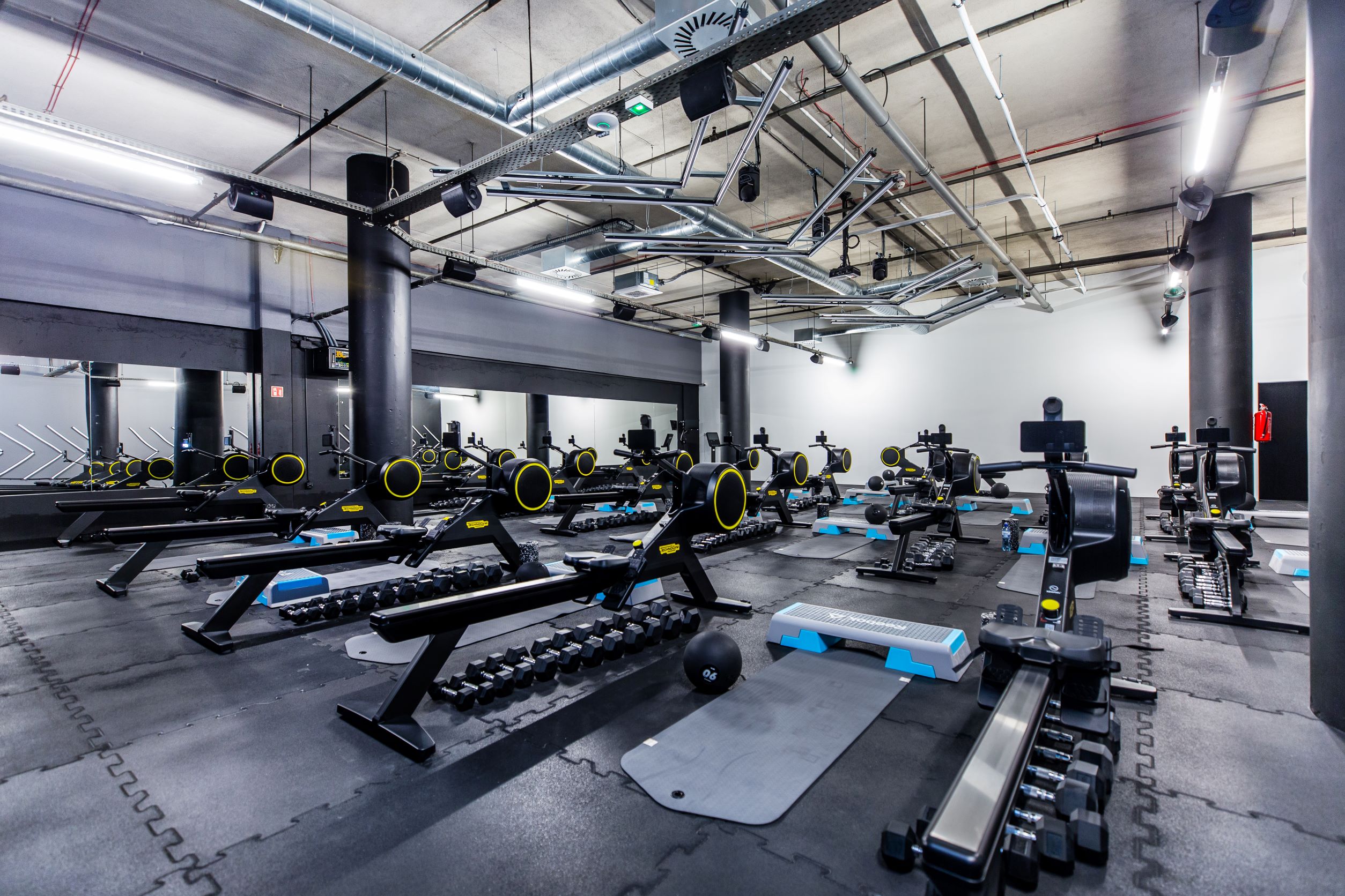 Specjalistyczna strefa do treningu funkcjonalnego i cardio w Well Fitness Zakopiańska w Krakowie z rzędem wioślarzy i akcesoriami do ćwiczeń.