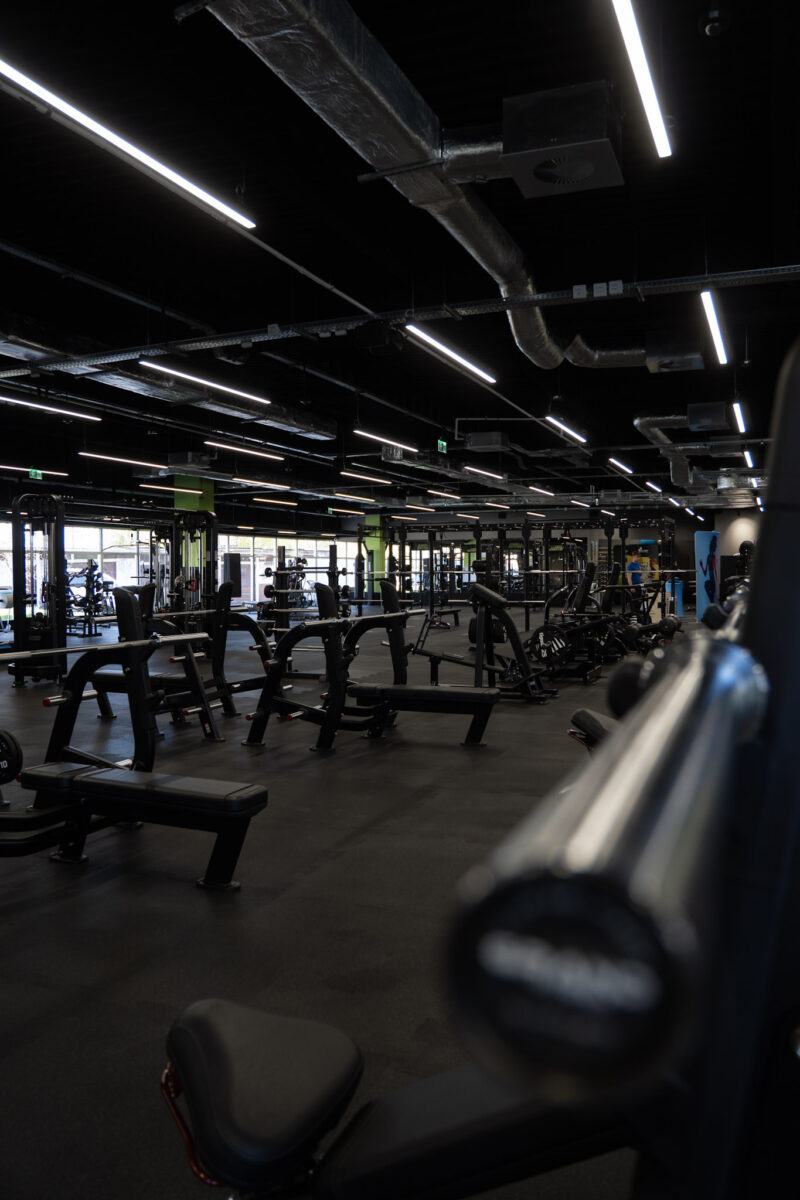 A perspective of the gym area with the training machines and benches visible, highlighting the large space and modern design of the gym.
